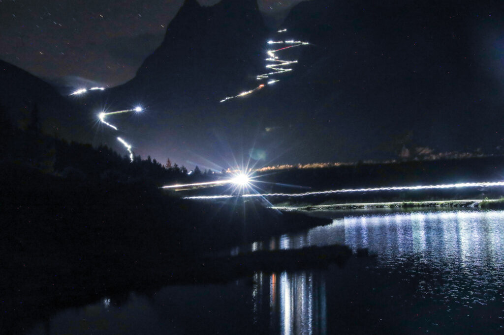 UTMB 2022 -vuorijuoksun yöosuuksilla otsalampuista syntyy tunnelmallinen valonauha vuorille.